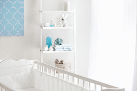 Beautiful light room with crib and toys on shelvesの写真素材