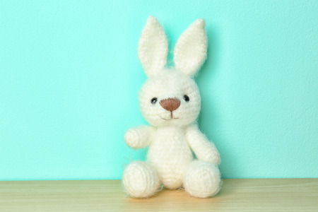 Cute knitted toy bunny on color backgroundの写真素材