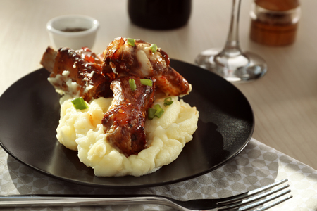 Plate with delicious pork ribs and mashed potatoes on tableの写真素材