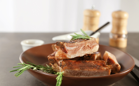 Plate with delicious pork ribs and rosemary on tableの写真素材