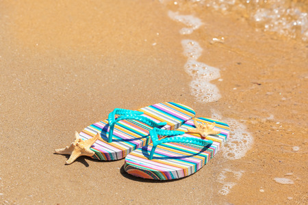 Colorful flip-flops and starfish on sand at sea shore. Vacation conceptの写真素材