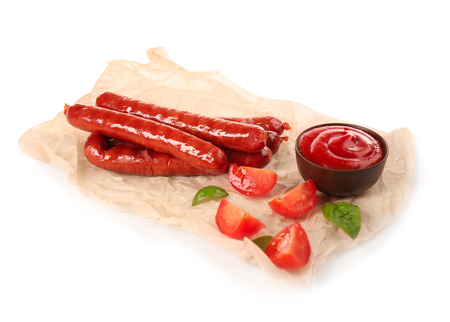 Parchment with roasted sausages and tomato sauce on white backgroundの写真素材