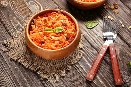 Bowl with delicious carrot raisin salad on wooden tableの写真素材