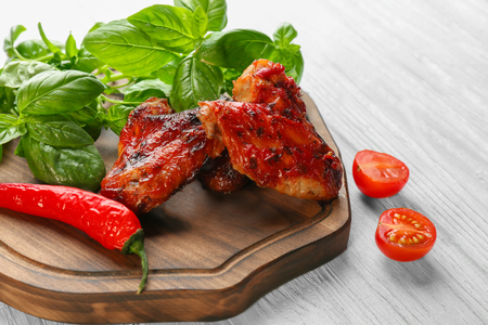 Tasty chicken wings in sauce on wooden boardの写真素材