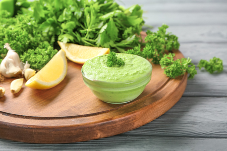 Delicious yogurt sauce in bowl with ingredients on wooden backgroundの写真素材