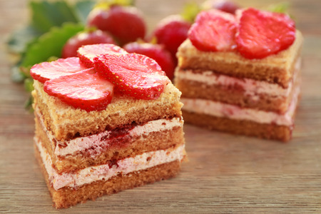 Two pieces of homemade cake with strawberries on wooden tableの写真素材