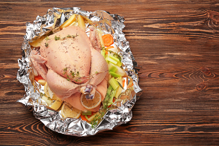 Whole raw turkey with other ingredients prepared to cook on wooden tableの写真素材