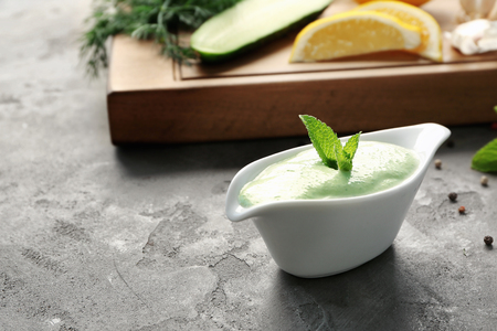 Delicious yogurt sauce in gravy boat with ingredients on grunge backgroundの写真素材