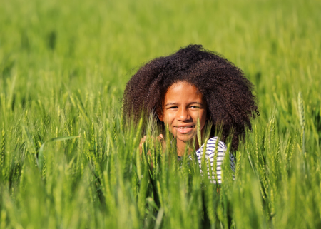 Happy little Afro American girl in green fieldの写真素材