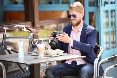 Young blogger working with camera at table, outdoorsの写真素材