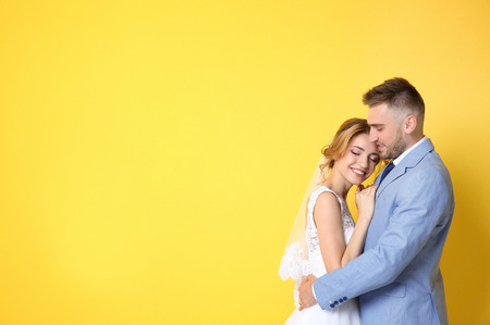 Happy wedding couple on color backgroundの写真素材
