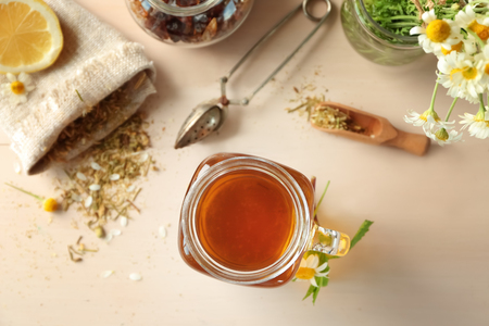 Mason jar with tasty chamomile tea on light wooden tableの写真素材