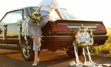 Beautiful young bride near decorated car outdoorsの写真素材