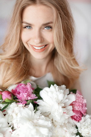Beautiful young woman with bouquet of peonies, closeupの写真素材