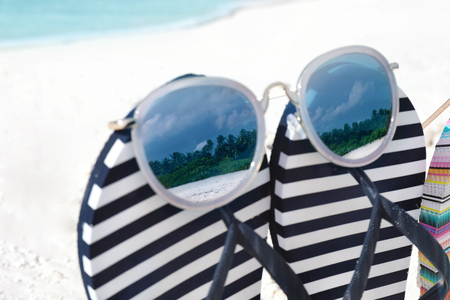 Striped flip-flops and sunglasses on sea shore, closeup. Summer vacation conceptの写真素材