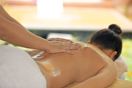 Beautiful young woman receiving massage in spa salonの写真素材