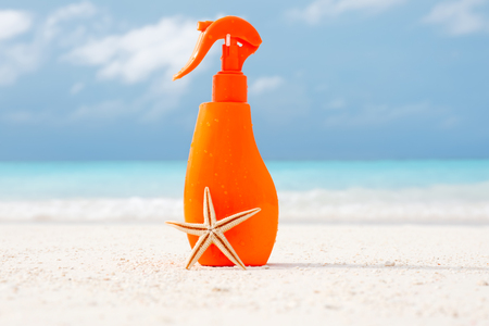 Bottle with sunscreen cream and starfish on sea shore. Summer vacation conceptの写真素材