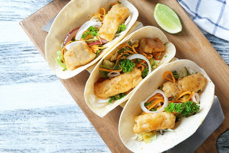 Stand with delicious fish tacos on wooden tableの写真素材