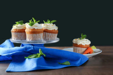 Glass stand with delicious carrot cupcakes on tableの写真素材
