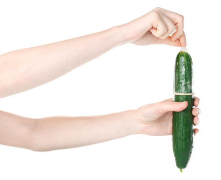 Female hands holding cucumber in condom on white background. Safe sex conceptの写真素材