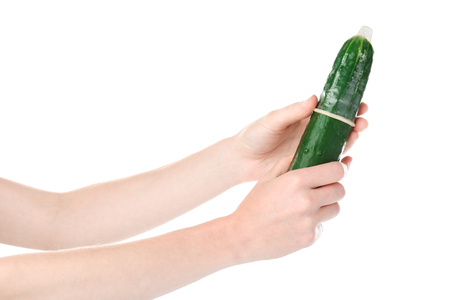Female hands holding cucumber in condom on white background. Safe sex conceptの写真素材