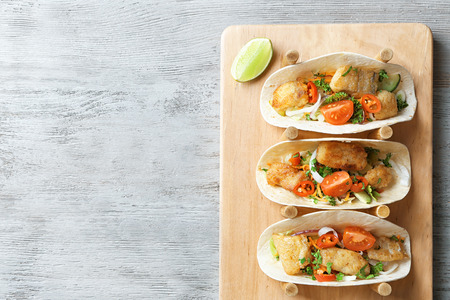 Stand with delicious fish tacos on wooden backgroundの写真素材