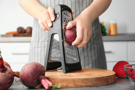Woman grating beetroot in kitchenの写真素材