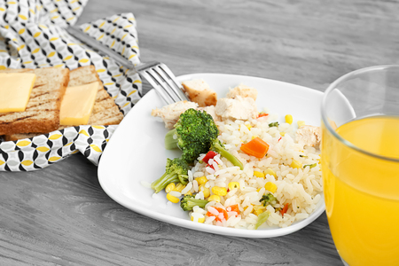 Plate with tasty rice, meat and vegetables near glass of juice on tableの写真素材