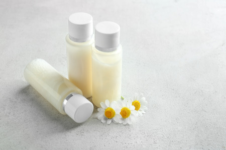Bottles with cream and chamomile flowers on table