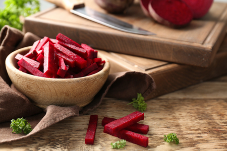 Bowl with sliced beetroot on wooden tableの写真素材