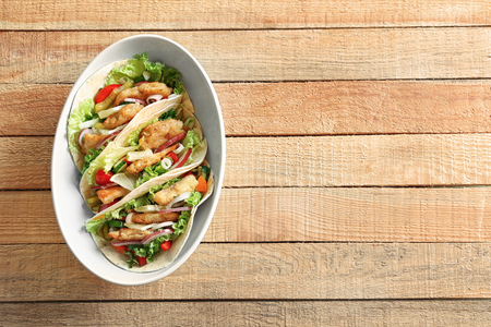 Bowl with delicious fish tacos on wooden tableの写真素材