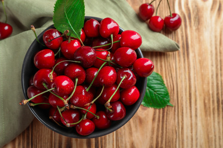 Bowl with tasty ripe cherries on wooden tableの写真素材