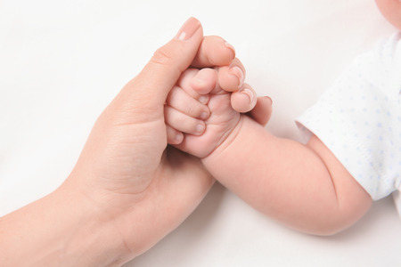 Mother holding newborn baby's hand on white background, closeupの写真素材