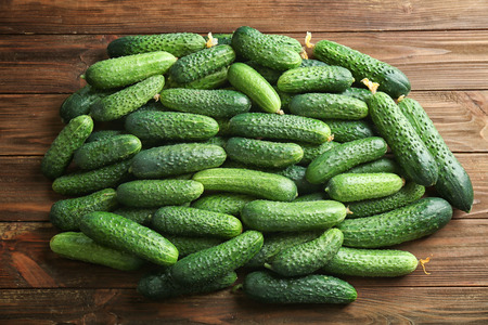 Many green fresh cucumbers on wooden backgroundの写真素材