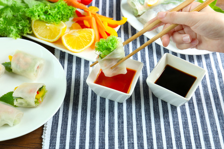 Female hand holding delicious spring roll with chopsticksの写真素材