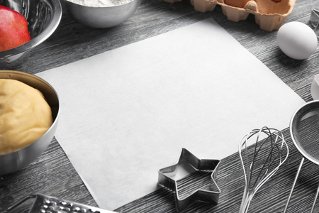 Parchment paper and raw dough with ingredients on kitchen tableの写真素材