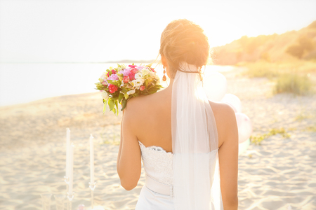 Beautiful bride with wedding bouquet on beachの写真素材