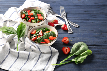 Bowls with strawberry spinach salad on tableの写真素材