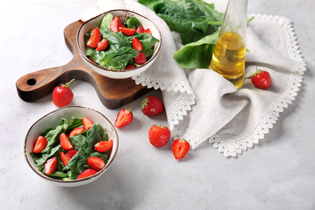Bowls with strawberry spinach salad on tableの写真素材