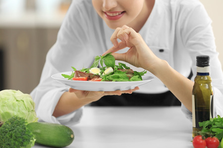 Young female chef with tasty dish in kitchenの写真素材