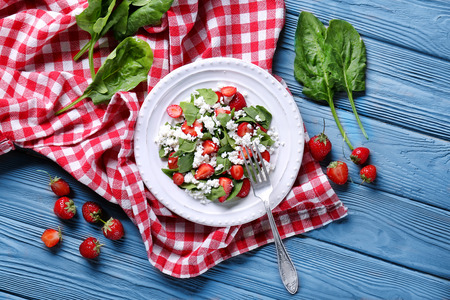 Plate with strawberry spinach salad on wooden tableの写真素材
