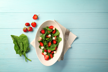 Plate with strawberry spinach salad on wooden tableの写真素材