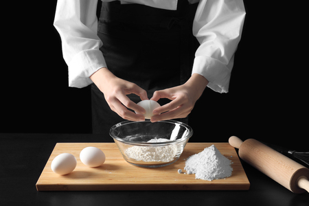 Young female chef cooking on dark backgroundの写真素材
