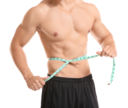 Sporty young man with measuring tape on white backgroundの写真素材