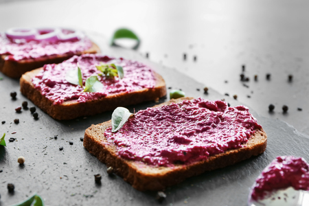 Bread with creamy beet hummus on slate plateの写真素材