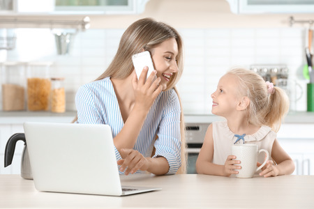 Busy young woman with her daughter at homeの写真素材