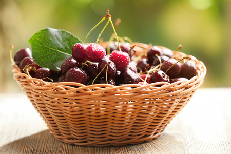 Wicker basket with fresh cherry on table outdoorsの写真素材