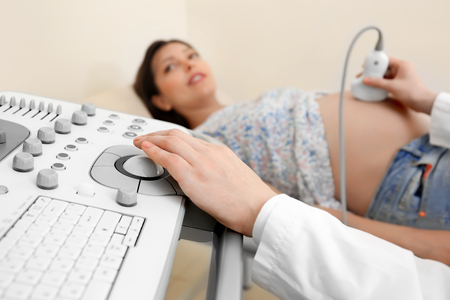 Doctor conducting ultrasound examination of pregnant woman in clinicの写真素材