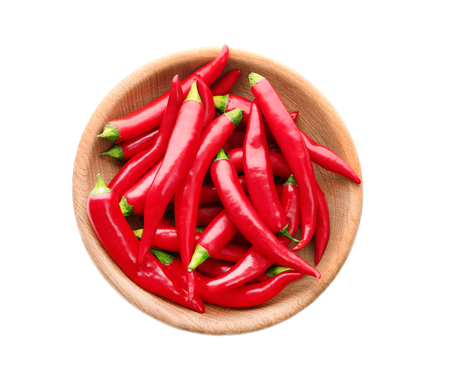 Many red chili peppers in wooden plate isolated on whiteの写真素材