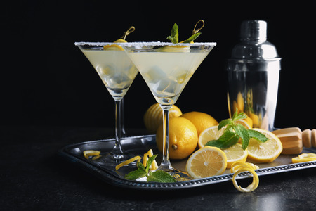 Glasses of lemon drop martini on metal tray against black backgroundの写真素材